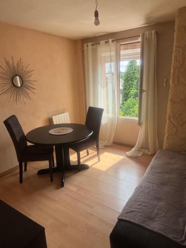 a dining room with a table and chairs and a window at Petit cocon in Château-Chinon