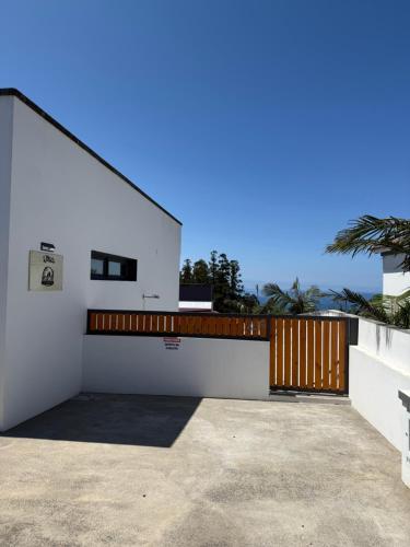 a white house with a wooden gate and a driveway at Quinta da Carlota in Povoação