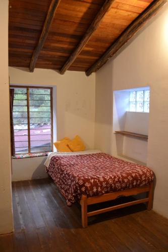 ein Schlafzimmer mit einem Bett und zwei Fenstern in der Unterkunft Cabaña rodeada de naturaleza en Ollantaytambo in Ollantaytambo