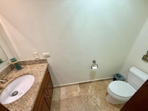 a bathroom with a white toilet and a sink at Depa en EDM planta baja a pie de playa in Mazatlán