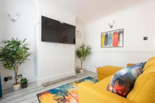 a living room with a yellow couch and a tv at Luna Homes in Dartford