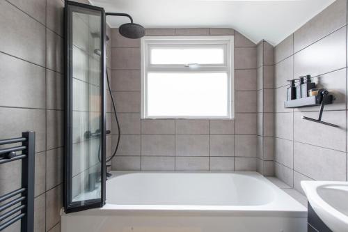 a bathroom with a bath tub and a window at Luna Homes in Dartford