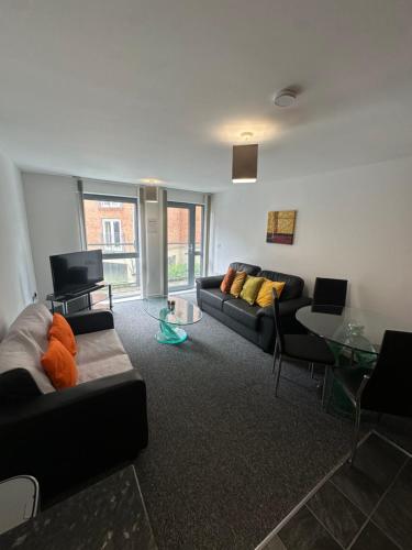 a living room with two couches and a glass table at 2 Bed ensuite with Balcony and Free onsite Secure Parking in Manchester