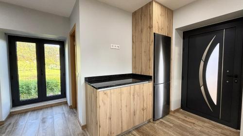 a kitchen with a black refrigerator next to a window at As Casas do Penedo da Moura in Arcos de Valdevez