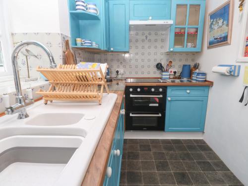 a kitchen with blue cabinets and a sink at 2 The Cottages in Ludgvan
