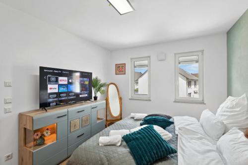 a bedroom with a bed and a flat screen tv at Harmonie Homes - Built in 2025 - Hotel-Quality Beds & Linen - Full Kitchen - Fiber WiFi - 4K Smart TV - 2 Balconies - Elevator - Free Private Parking - Near Augsburg - 20 Min via Autobahn to Munich-West in Dasing