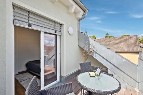 a balcony with a table and chairs and a window at Harmonie Homes - Built in 2025 - Hotel-Quality Beds & Linen - Full Kitchen - Fiber WiFi - 4K Smart TV - 2 Balconies - Elevator - Free Private Parking - Near Augsburg - 20 Min via Autobahn to Munich-West in Dasing