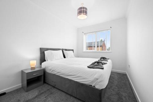 ein weißes Schlafzimmer mit einem Bett und einem Fenster in der Unterkunft Three Bedroom House by Brookland Stays Serviced Accommodation Short Lets Wigan with Free WiFi in Hindley