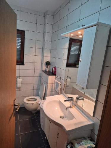 a bathroom with a sink and a toilet and a mirror at Apartman Pecara in Široki Brijeg