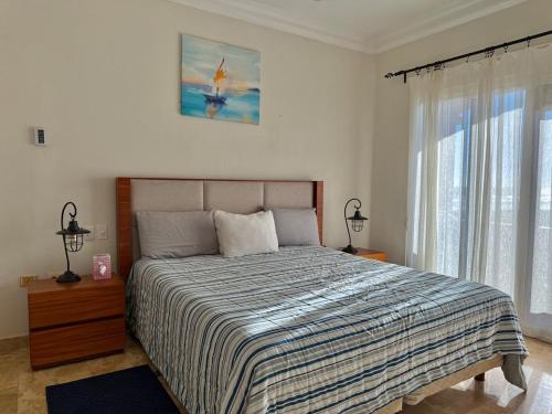 a bedroom with a bed with a striped comforter at Depa Frente a la Playa con Vistas en EDM in Mazatlán