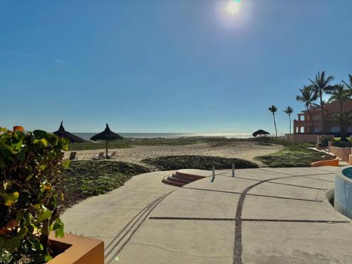 a walkway to a beach with umbrellas and the ocean at Depa Frente a la Playa con Vistas en EDM in Mazatlán