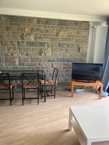 a living room with chairs and a table and a brick wall at Taunus Wohnen und Arbeiten mit eigener Terrasse in Friedrichsdorf