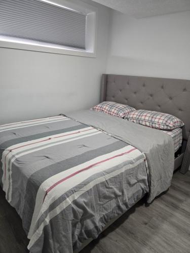 a bed sitting in a bedroom with a window at Cozy One bedroom BSMT Apartment in Edmonton