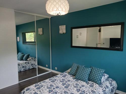 a bedroom with blue walls and a couch and a mirror at Chambre calme à la limite de Belfort, maison avec jardin proche du stade, du skatepark et de la rivière in Offemont