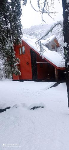 a red house with snow on top of it at Cabañas en Termas de Chillán in Recinto