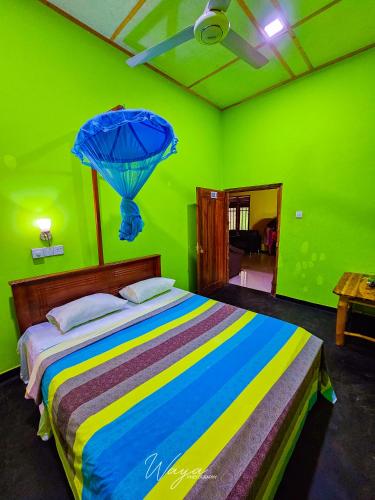 a green bedroom with a bed with a blue umbrella at Elephant paradise Safari lodge in Udawalawe