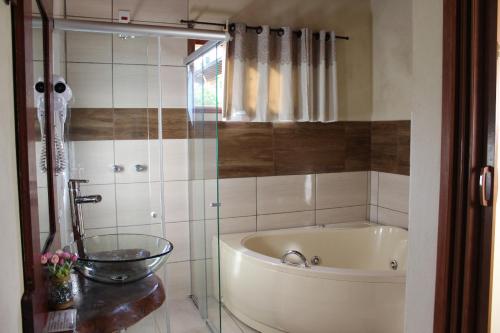 a bathroom with a tub and a glass shower at Verde Mauá Chales in Visconde De Maua