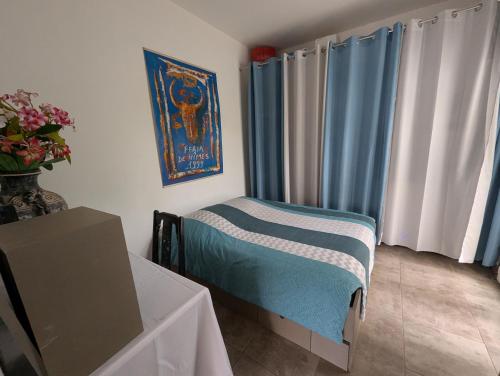 Cette chambre comprend une table et un lit avec des rideaux bleus. dans l'établissement La Maison du Soleil & du Calme Centre-ville à Pied Parking Privé à Nîmes !, à Nîmes