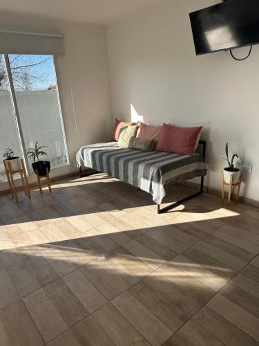 Una sala de estar con una cama y una gran ventana. en EnSueños Tandil, en Tandil