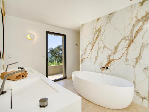 une salle de bain blanche avec une baignoire et un lavabo dans l'établissement Vue Saint Tropez, à Grimaud
