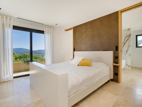 une chambre avec un lit blanc et une grande fenêtre dans l'établissement Vue Saint Tropez, à Grimaud
