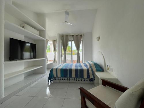 a white room with a bed and a tv at Casa del Sol in Santa Cruz Huatulco