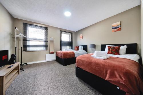 a bedroom with two beds and a television in it at RELAXED CENTRAL HOUSE LOCATED IN WEST READING CLOSE TO TOWN CENTRE with FREE DRIVE WAY PARKING, WI FI & NETFLIX BY AI ESTATE GROUP in Reading
