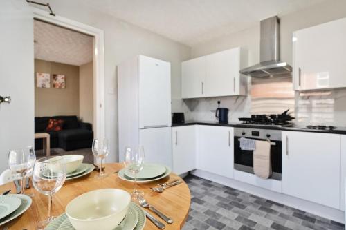 a kitchen with a wooden table with wine glasses on it at RELAXED CENTRAL HOUSE LOCATED IN WEST READING CLOSE TO TOWN CENTRE with FREE DRIVE WAY PARKING, WI FI & NETFLIX BY AI ESTATE GROUP in Reading
