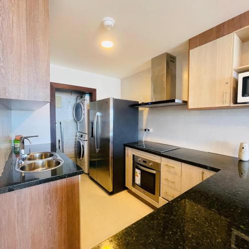 a kitchen with a sink and a stainless steel refrigerator at Hermoso departamento con vista al mar en Salinas! in Salinas