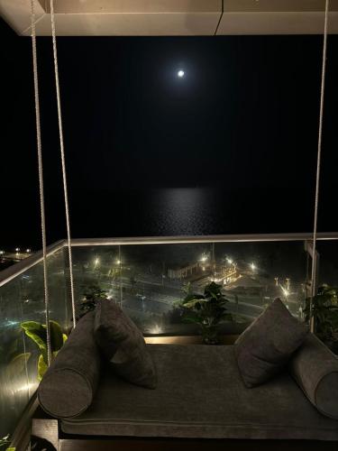 a hanging couch with pillows on a balcony at night at برج داماك الكورنيش جدة - Damac Tower Corniche Jeddah in Jeddah