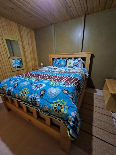 a bedroom with a wooden bed with a blue comforter at La Casita De La Cueva in Cabo Rojo