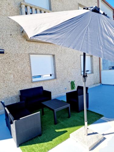 a patio with a table and chairs and an umbrella at Apartamento Calma in Negreira