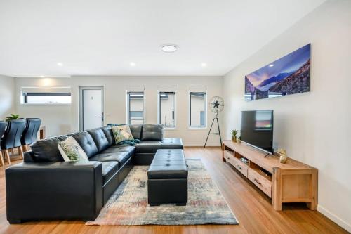 a living room with a black couch and a flat screen tv at Villa No 5 Brand New close to shops 10 min Airport in Warrane