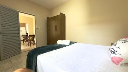 a bedroom with a white bed and a table at Casa Aconchegante Sete Lagoas - 35A in Sete Lagoas