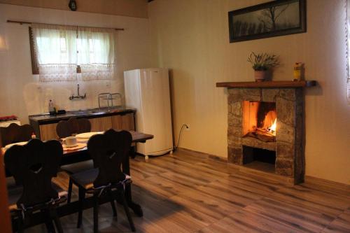 a kitchen with a fireplace and a table and a refrigerator at Verde Mauá Chales in Visconde De Maua