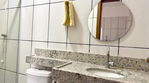 a bathroom with a sink and a mirror and a toilet at Casa 3Km do centro Sete Lagoas - 35 in Sete Lagoas