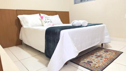a bedroom with a bed with white sheets and a rug at Casa 3Km do centro Sete Lagoas - 35 in Sete Lagoas