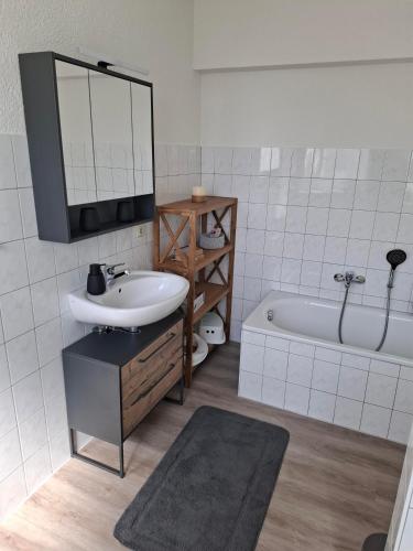 ein Badezimmer mit Waschbecken, Spiegel und Badewanne in der Unterkunft ZWEITE REIHE FLAIR Ferienwohnungen in Krakow am See