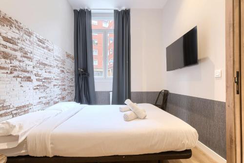 a bedroom with a bed with a tv on the wall at Pension H30 Tiboli Self Checkin in Bilbao
