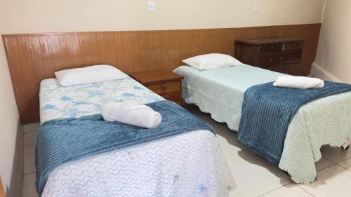 a room with two beds with towels on them at Casa 3Km do centro Sete Lagoas - 35 in Sete Lagoas