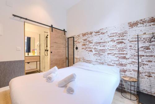 a white bed in a room with a brick wall at Pension H30 Tiboli Self Checkin in Bilbao