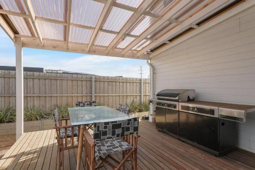 a patio with a grill and a table with chairs at Surf Mist at Surf Beach in Surf Beach