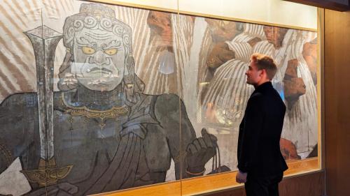 a man standing in front of a painting of a statue at Sakan in Sendai