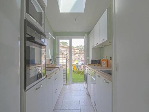 une cuisine avec des placards blancs et une grande fenêtre dans l'établissement Holiday Home in Isigny-sur-Mer with Garden, cleaning included, à Isigny-sur-Mer
