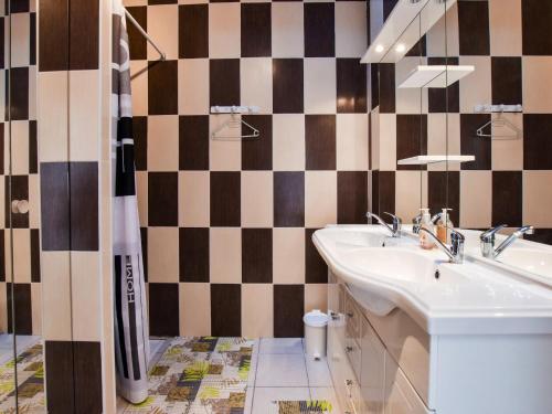 La salle de bains est pourvue d'un lavabo et d'un mur en damier. dans l'établissement Holiday Home in La Teste with Pool & BBQ, cleaning included, à La Teste-de-Buch