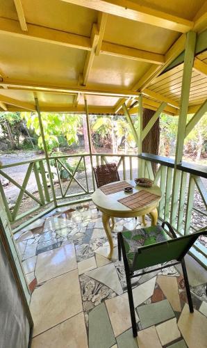 a room with a table and chairs on a balcony at Real Jamaica - 5 Cabins right beside the sea in Oracabessa