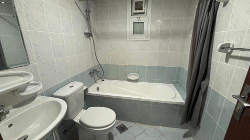 a bathroom with a toilet and a tub and a sink at Trendy Studio In Orient Towers Ajman in Ajman 