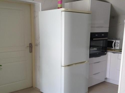 - un réfrigérateur blanc dans une cuisine avec des placards blancs dans l'établissement Holiday Home in Dax near Train Station, cleaning included, à Dax