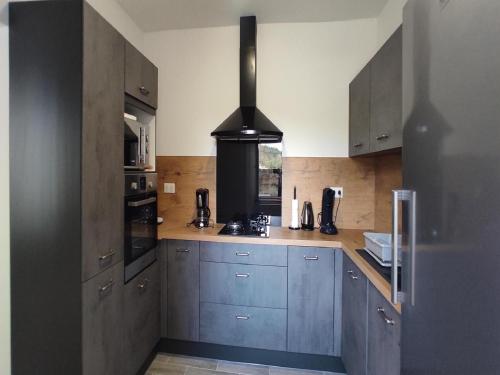 - une cuisine avec des placards gris et une cuisinière noire dans l'établissement Farmhouse in Ardèche near Vallon Pont d'Arc, cleaning included, à Sanilhac