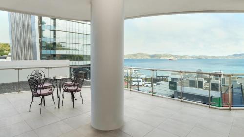 a balcony with a table and chairs and a view of the water at Crowne Plaza Residences Port Moresby by IHG in Port Moresby